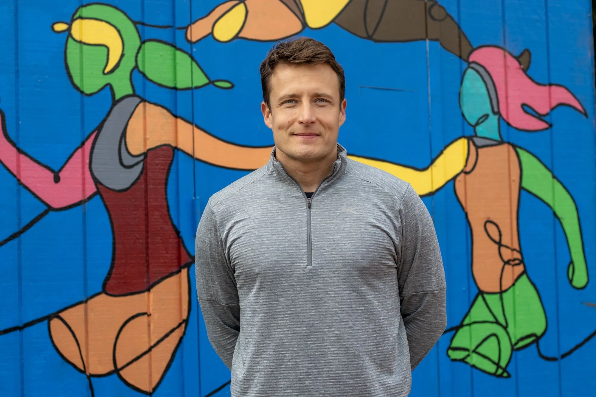 Dario Mathias in front of a mural of athletes