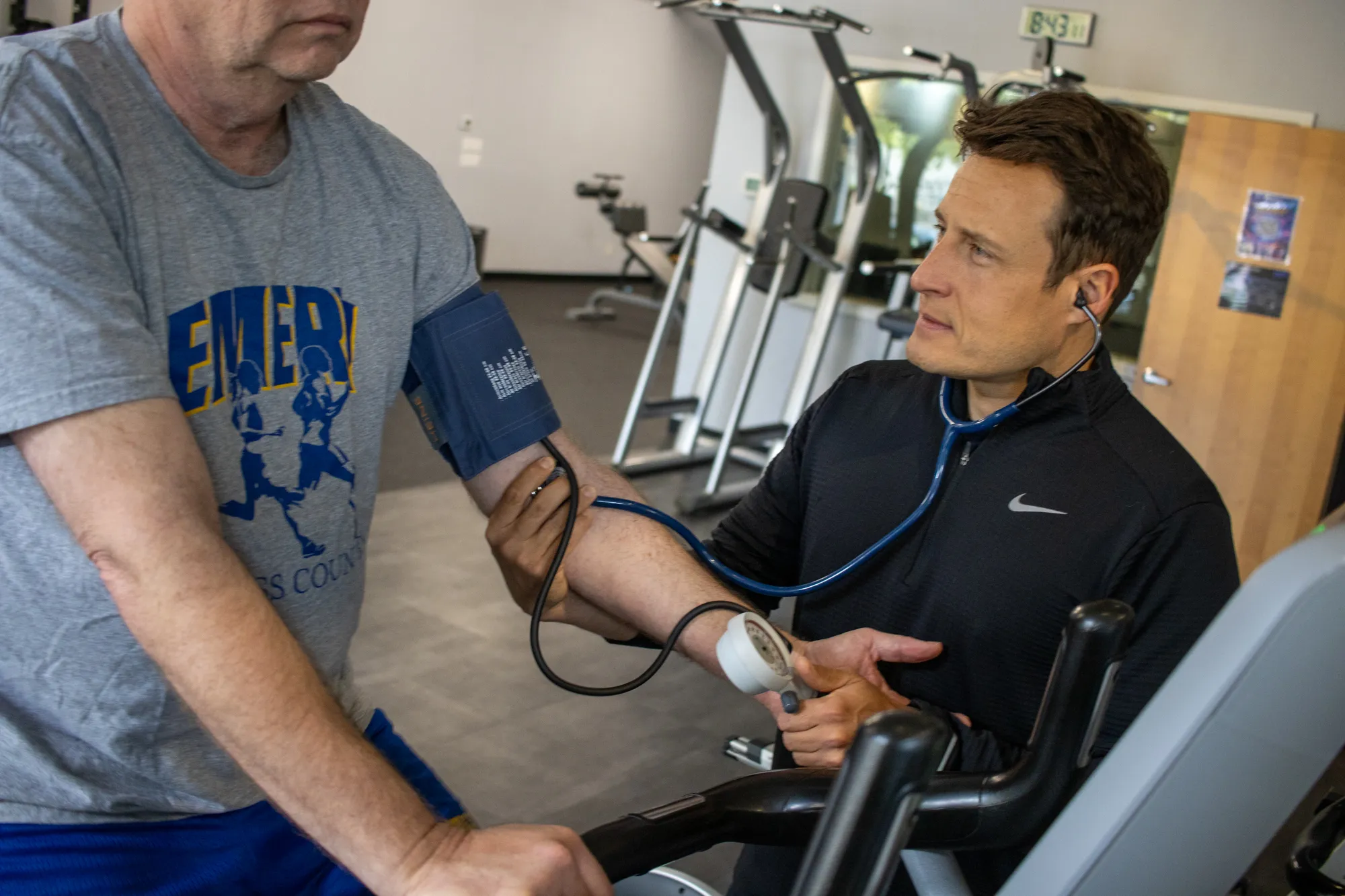 Dario checking a senior client's blood pressure during a session