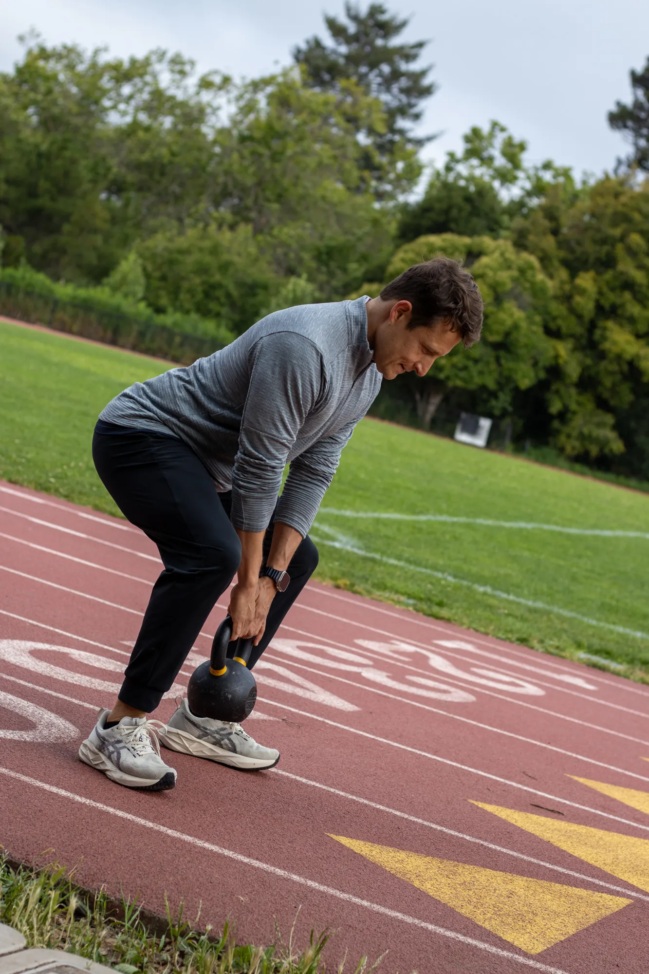 Dario setting up a kettlebell deadlift on an outdoor track