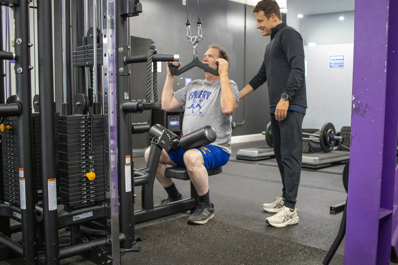 Dario guiding a senior client through a strength machine