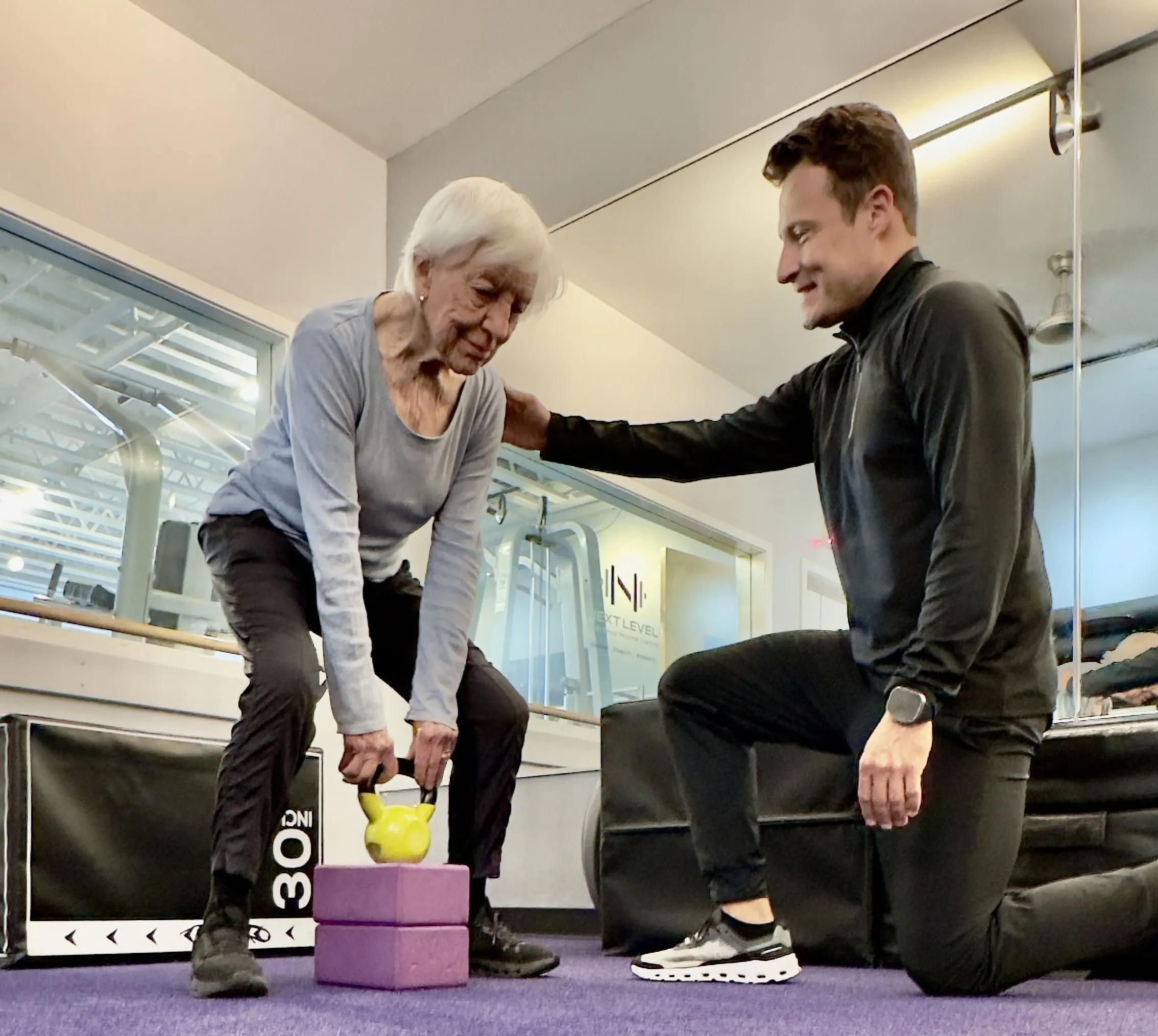 Dario coaching a senior client through a kettlebell deadlift